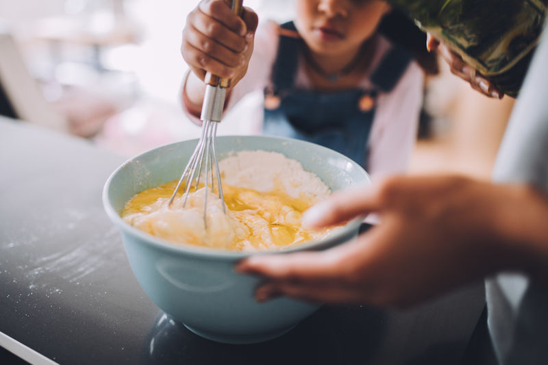 Midsection of mother and daughter preparing food in bowl