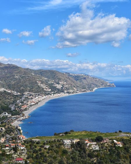 Aerial view of city by sea against sky