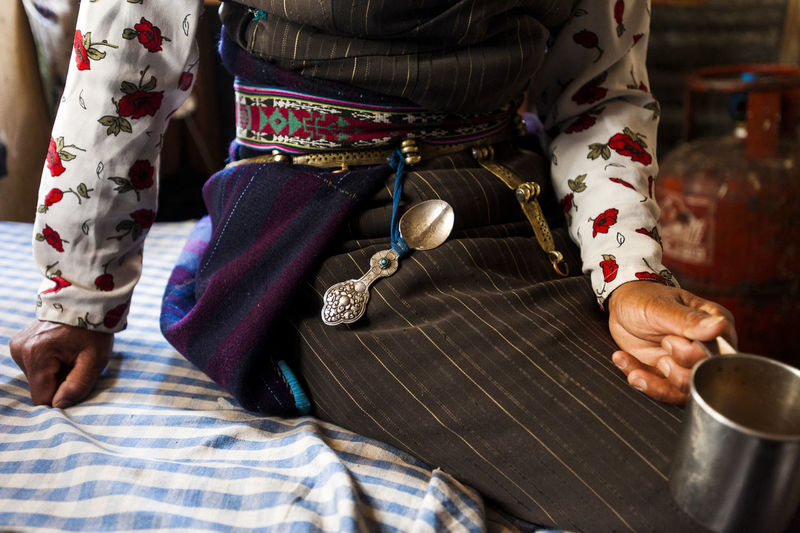 A nepali woman sits on a bed wearing the traditional  'pangden',woven woollen apron30th may 2009 