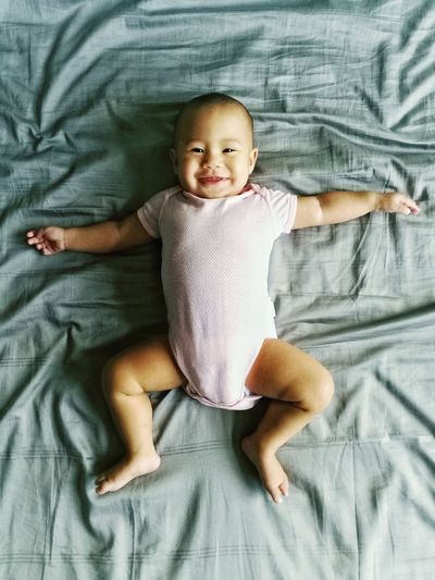 Portrait of cute baby girl lying on bed