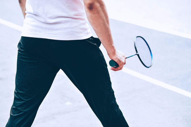 Midsection of man playing badminton at sports court