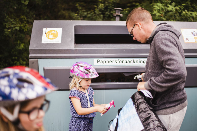 Father and daughter putting rubbish into recycling bin