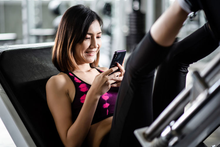 Woman using mobile phone while exercising in gym