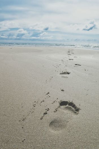 Footprints on sandy beach towards sea