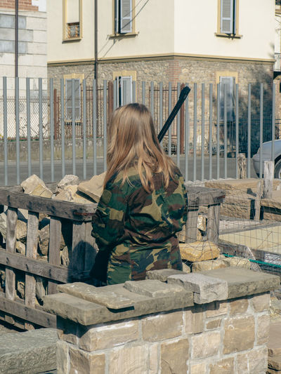 Soldier girl on a checkpoint holding a rifle gun and wearing a camo green military uniform