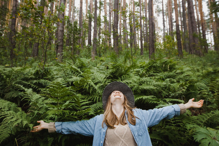 Cheerful woman enjoying freedom in green forest