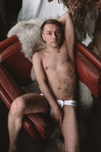 Portrait of naked man lying down on fur