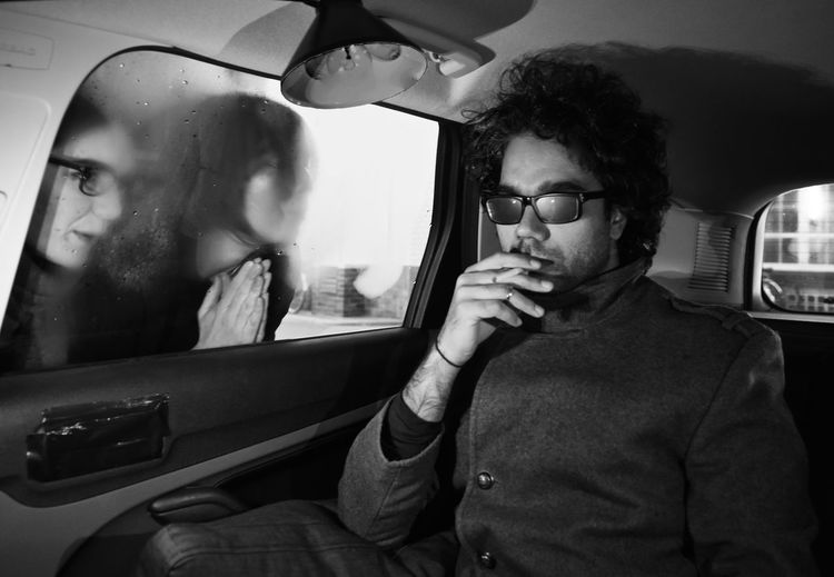 Women looking at man smoking cigarette in car