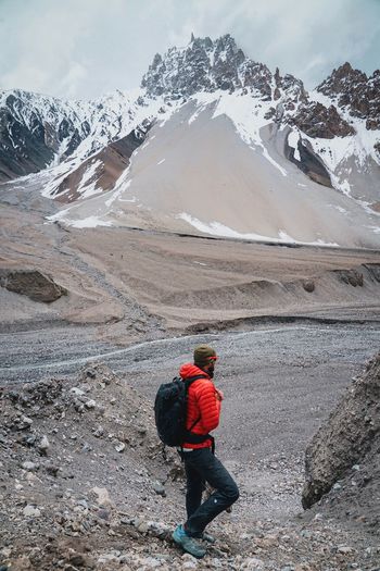 Rear view of man walking on snowcapped mountain