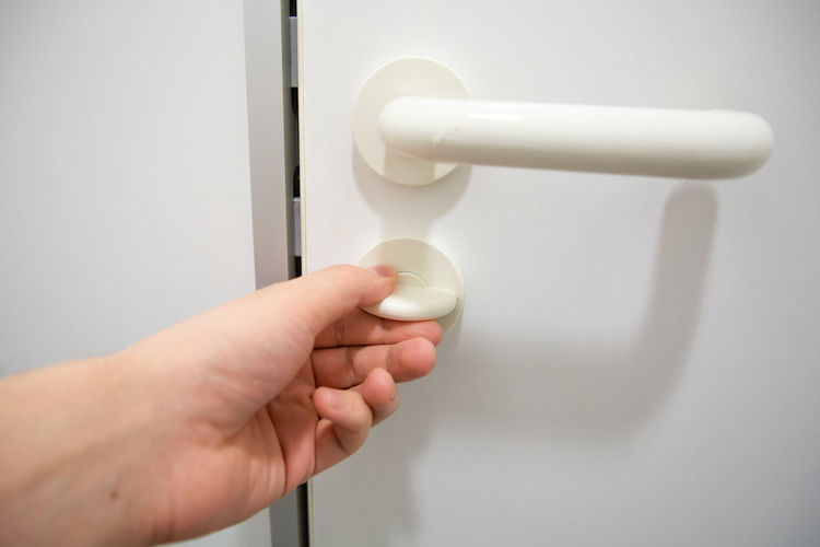 Human hand close doorknob of public restroom door to have privacy inside the cabin 