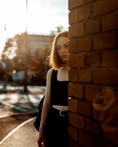 Woman standing against brick wall in city