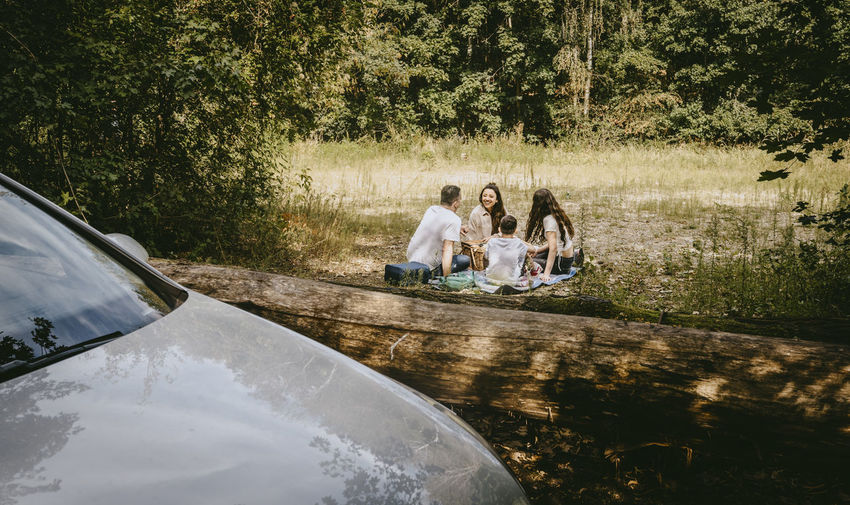 Family spending leisure time while sitting in forest during vacation