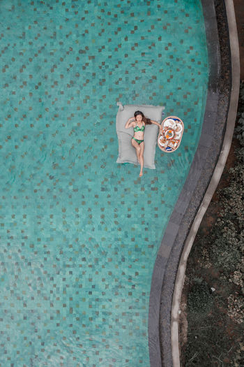 High angle view of woman standing by swimming pool