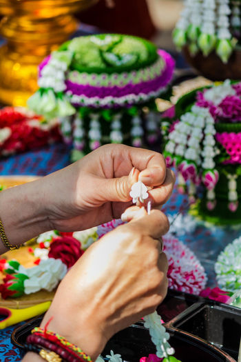 Cropped hands of woman making floral garland