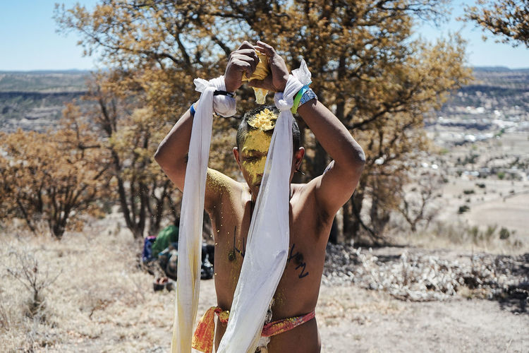 Shirtless man with textiles standing on land