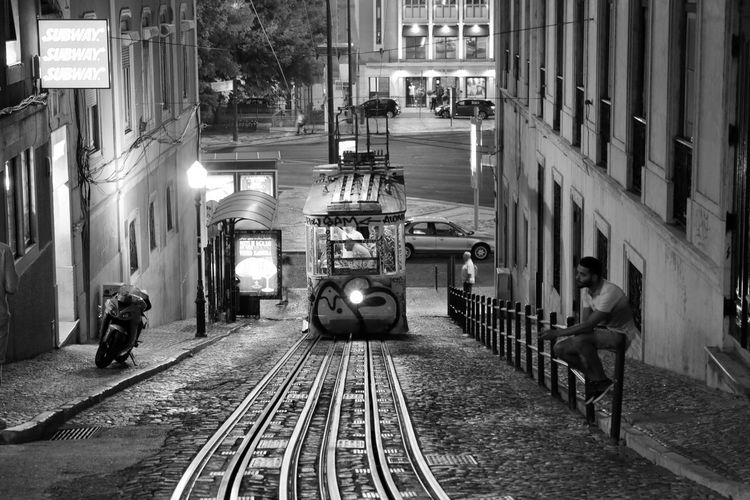 People on railroad tracks amidst buildings in city