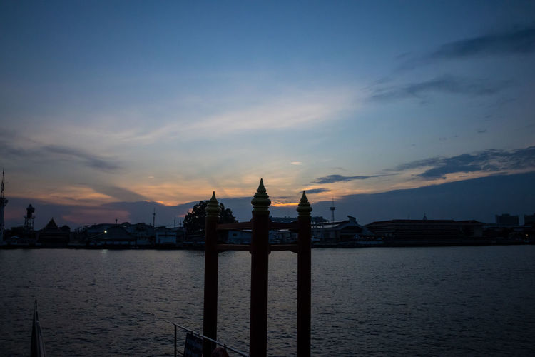 Silhouette of city at waterfront during sunset