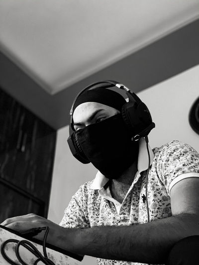 Full length portrait of young man wearing mask and headphone 