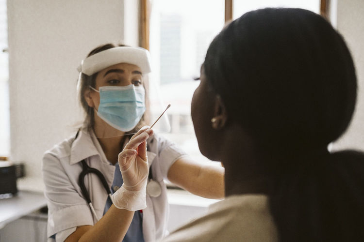 Female doctor wearing protective mask and face shield doing patient's medical test