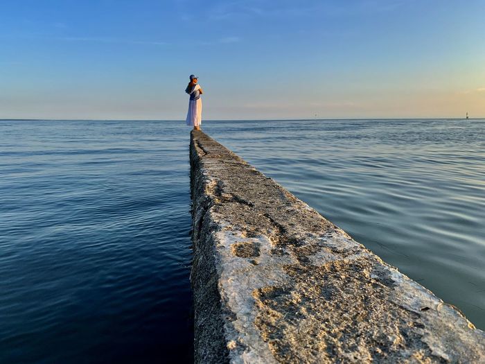 Woman standing on sea against sky
