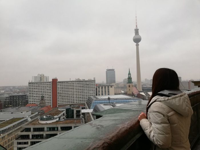 Side view of woman looking at modern buildings in city