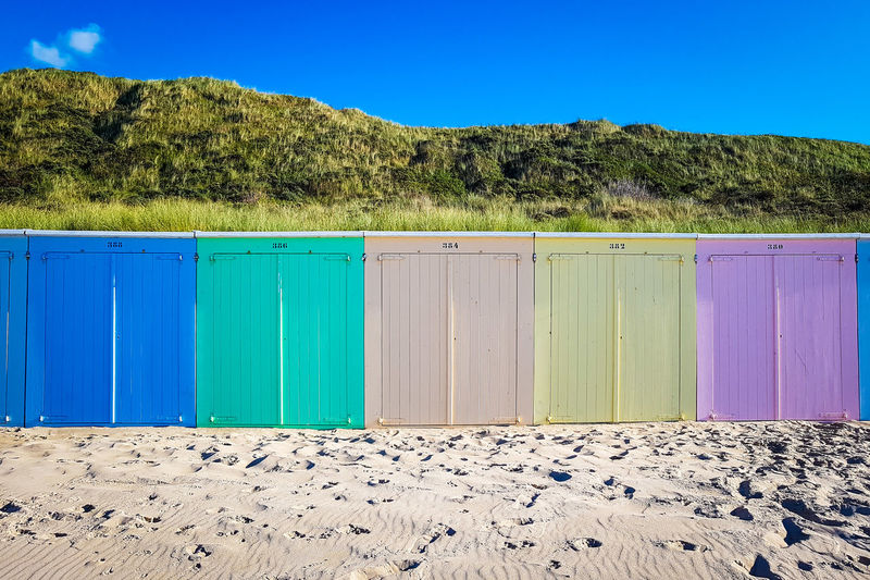Scenic view of beach with colorful wooden huts against clear blue sky