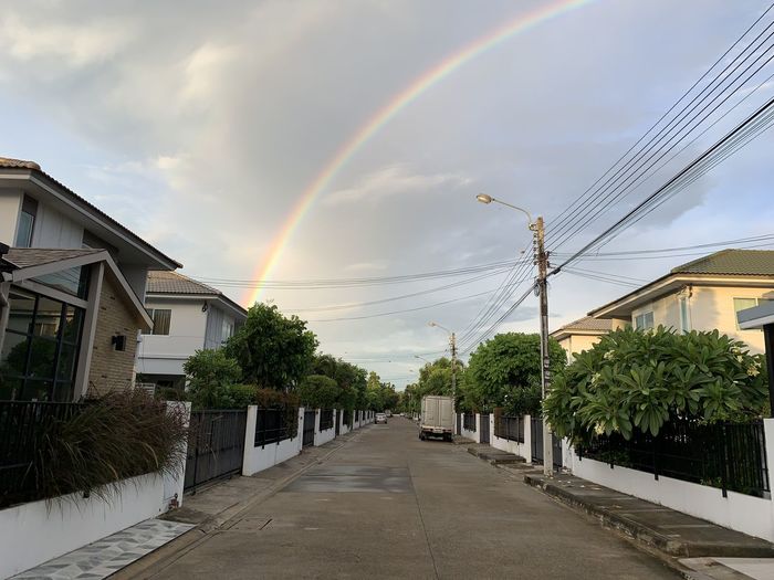 Rainbow over street amidst buildings against sky