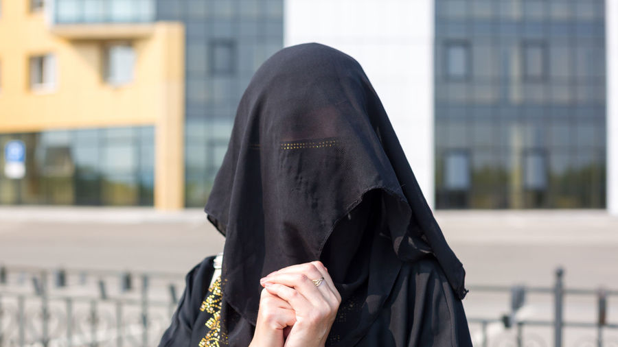 Portrait of muslim woman in national clothes covering her face in a european city.