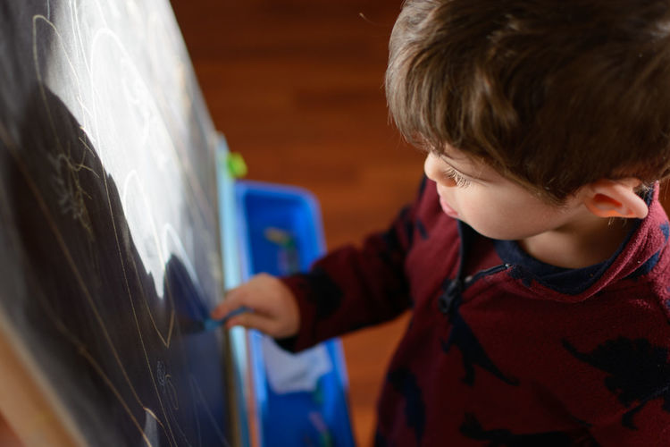 Close-up of boy drawing on blackboard