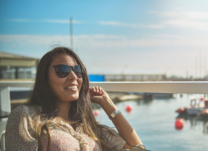 Portrait of young woman in sunglasses against sky
