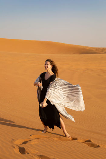 Full length of young woman on sand dune in desert