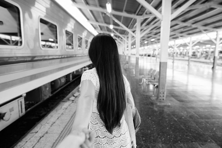 Rear view of woman standing at railroad station