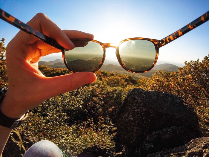 Close-up of hand holding sunglasses against clear sky