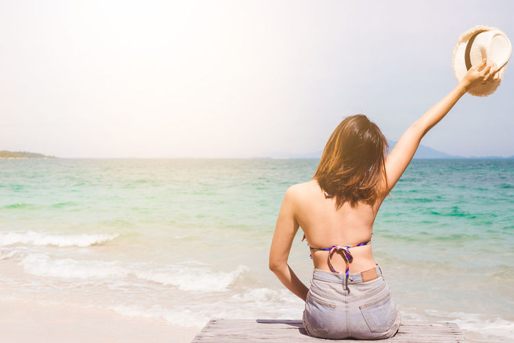 Rear view of man on beach against sky