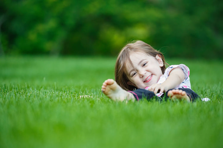 Happy child laying in perfectly manicured lush green organic lawn