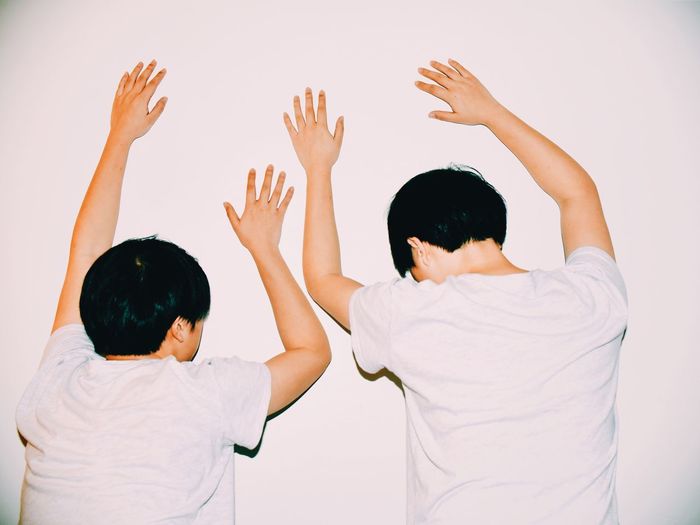 Rear view of boys leaning on white wall