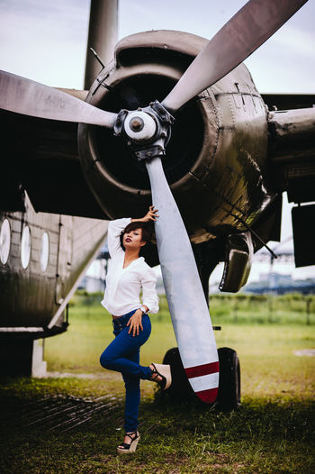 Woman standing against airplane on field