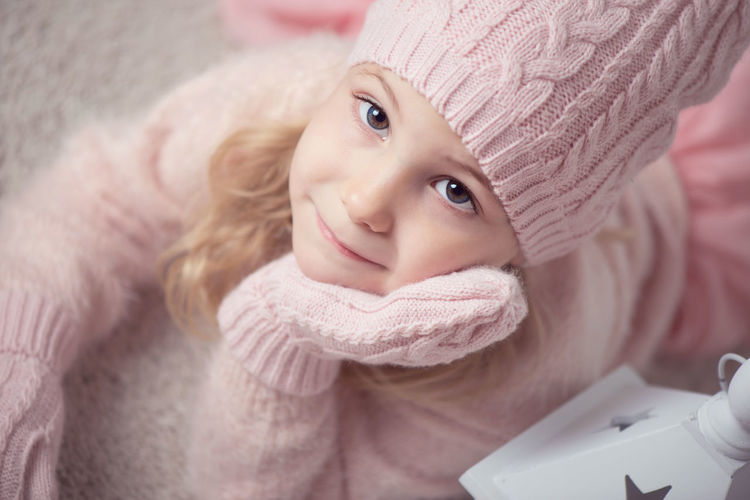 Close-up portrait of cute girl wearing warm clothing at home