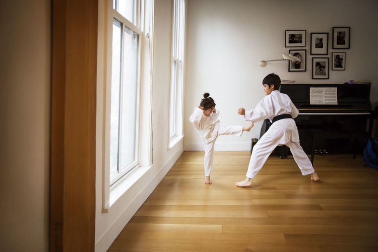 Siblings practicing karate by window at home