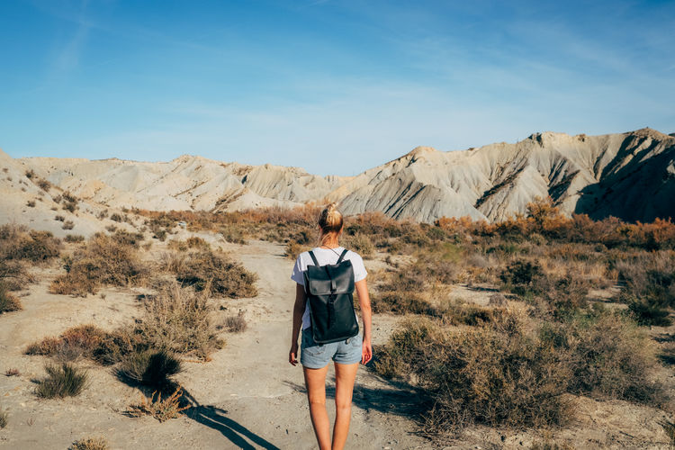 Rear view of woman walking on desert against sky