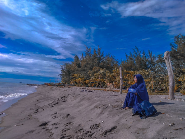 Full length of woman on beach against blue sky