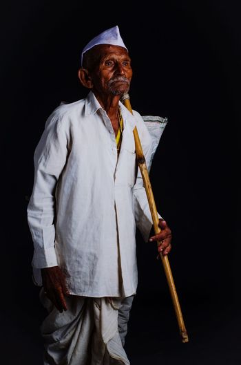 Senior man standing against black background