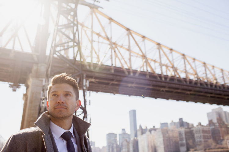 Portrait of young businessman standing near a bridge in an urban environment