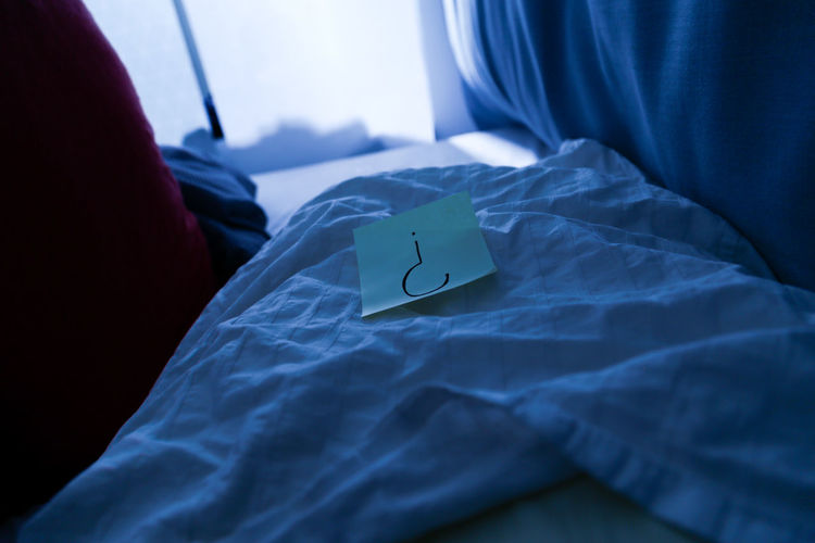 Close-up of paper with question mark on bed