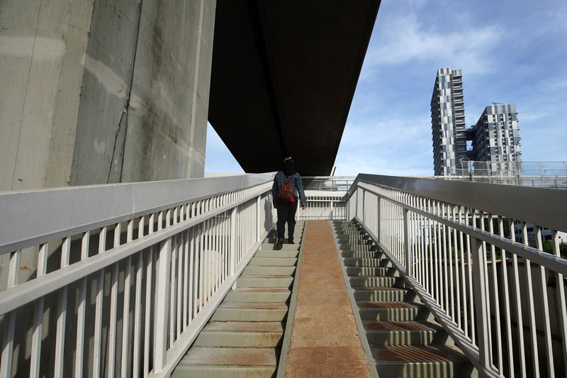 Man walking on bridge against sky in city