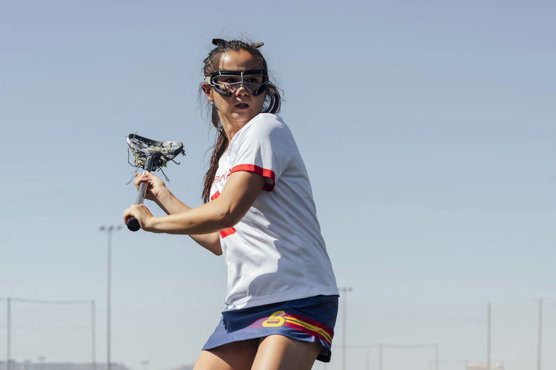 Determined player playing lacrosse in front of clear sky