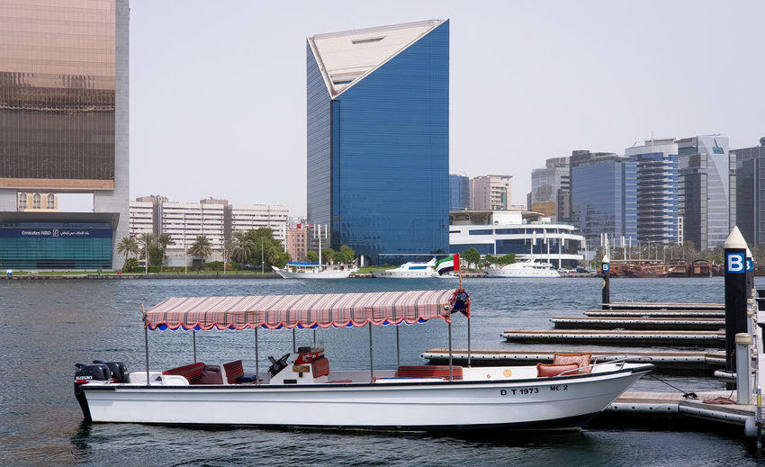 Boats in modern buildings against clear sky
