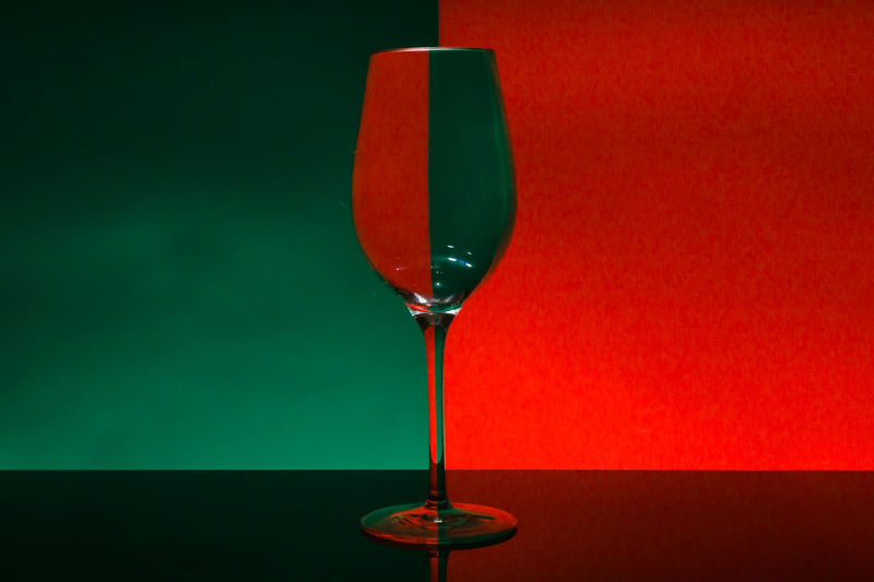Close-up of wineglass on table against red background