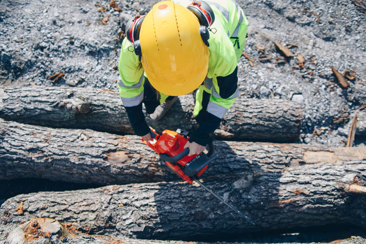 Close-up of man cutting tree trunk