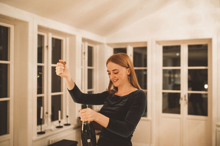 Young woman opening bottle of champagne